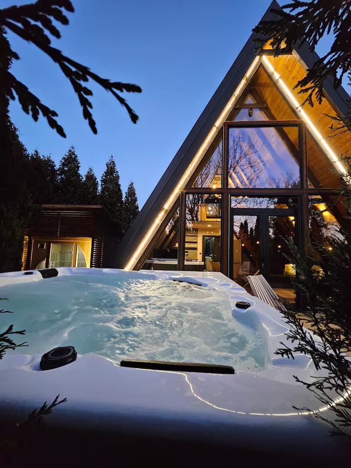 A-frame cabin at dusk with purple sky and warm facade